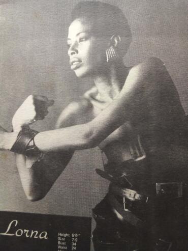 Black-and-white portrait of a woman with short hair, wearing statement earrings, leather gloves, and a bracelet.