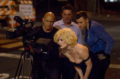Filmmakers review a scene with a blonde actress on a movie set at night.