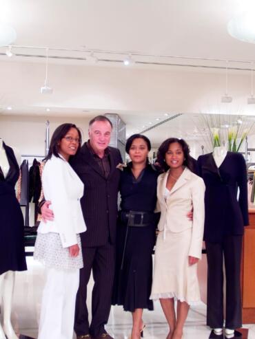Group of four diverse women and a man in professional attire inside a clothing store.