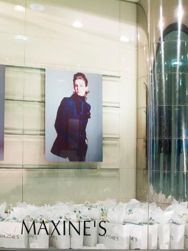 Display window with fashion posters and a mannequin dressed in a white outfit.