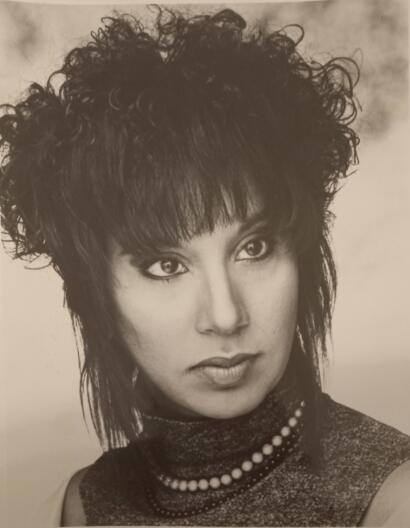 Elegant black-and-white portrait of a woman with voluminous, curly hair and striking makeup.