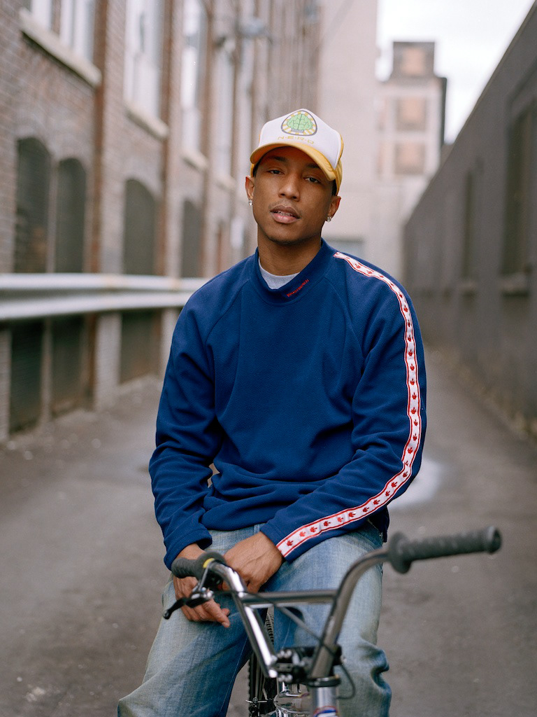 Young man wearing a blue sporty sweatshirt, sitting on a bicycle in an urban alleyway.