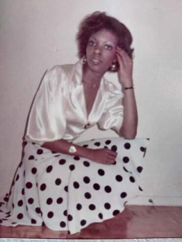 Vintage portrait of a woman in a silk blouse and polka dot skirt, sitting on the floor.