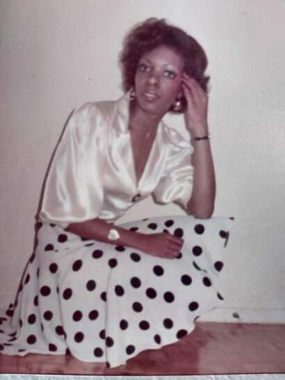 Vintage portrait of a woman in a silk blouse and polka dot skirt, sitting on the floor.