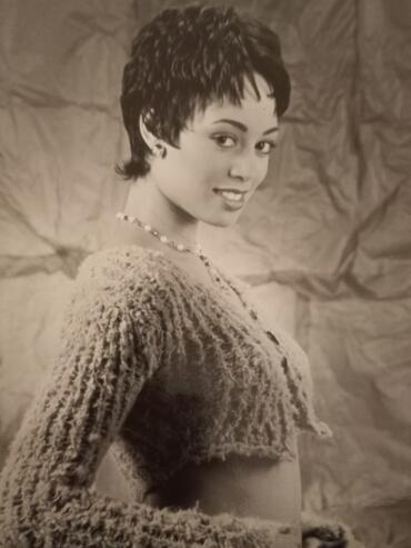 Elegant woman with a textured sweater and short hairstyle, adorned with a pearl necklace.