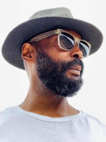 Man wearing a stylish gray hat and oversized sunglasses, captured in side profile.