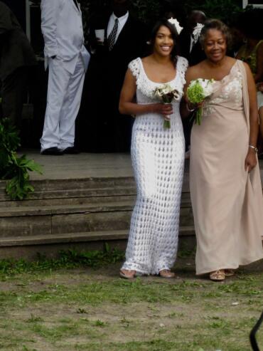 Women in elegant dresses holding bouquets at a wedding ceremony.