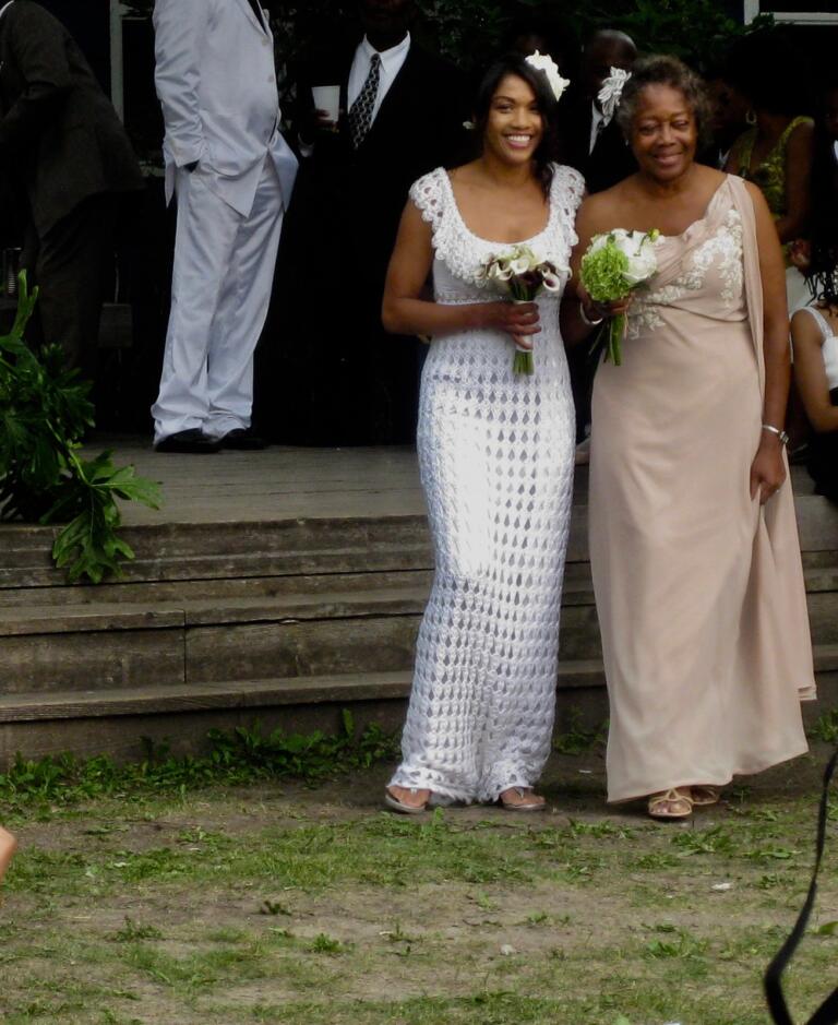 Women in elegant dresses holding bouquets at a wedding ceremony.