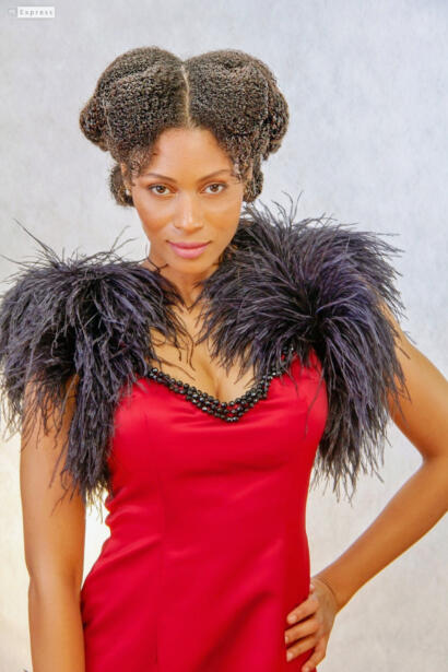 Woman in a red dress with feathered black shoulder accents, styled in vintage-inspired hair.