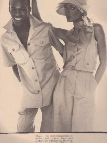 Black and white photo of Denise McLeod standing beside Calvin French, the two Black supermodels of their time, their arms around each other, both wearing vintage House of Lorraine fashions, 1976