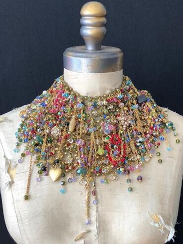 Elegant collection of layered, colorful statement necklaces on a vintage mannequin.