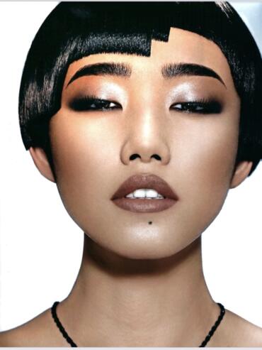 Close-up of a woman with sleek black bob haircut, shimmering eye makeup, and nude lipstick.