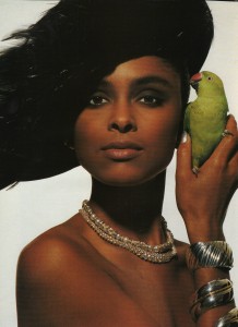 Gold jewelry, bold makeup, and a green parrot perched on her finger.