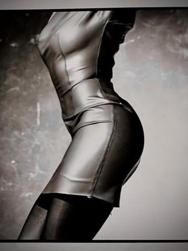 Close-up of a person wearing a sleek, shiny leather dress and thigh-high stockings.