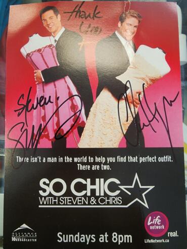 Promotional poster for "So Chic with Steven & Chris," featuring two men in suits, holding large, pink champagne glasses.