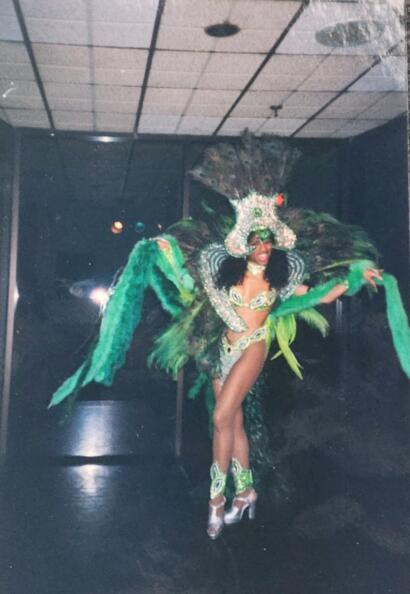 A performer in a vibrant green feathered costume with intricate detailing and high heels.