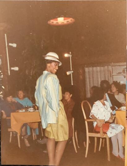Fashionable woman in vintage-inspired outfit posing in a cozy indoor restaurant setting.