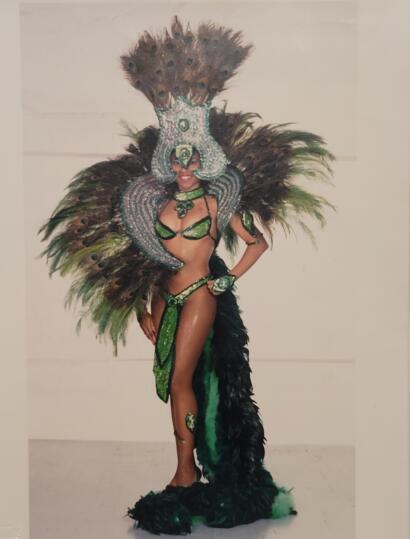 Woman in elaborate peacock-inspired costume with feathers and jewelry.