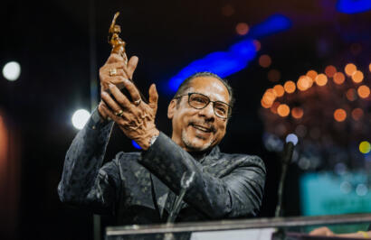 Man holding an award on stage at a formal event.