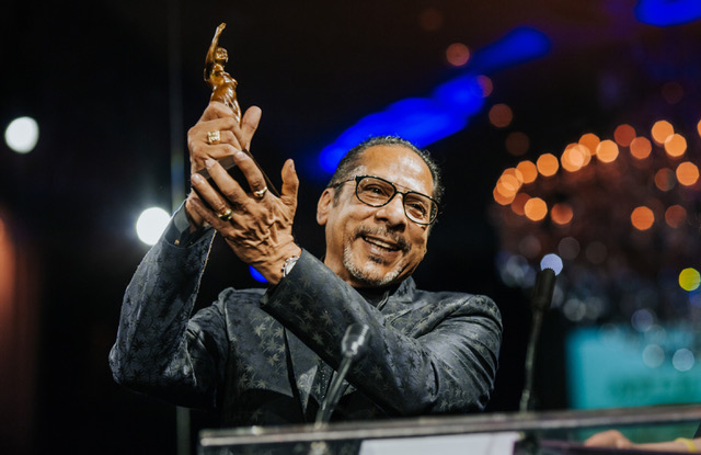 Man holding an award on stage at a formal event.