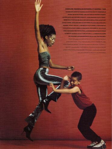 A woman and a boy engage in a playful, fashion-forward moment against a red background.