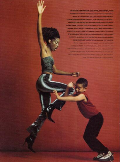 A woman and a boy engage in a playful, fashion-forward moment against a red background.