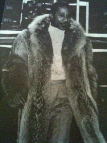 Woman wearing a luxurious fur coat and stylish pants in a vintage setting.