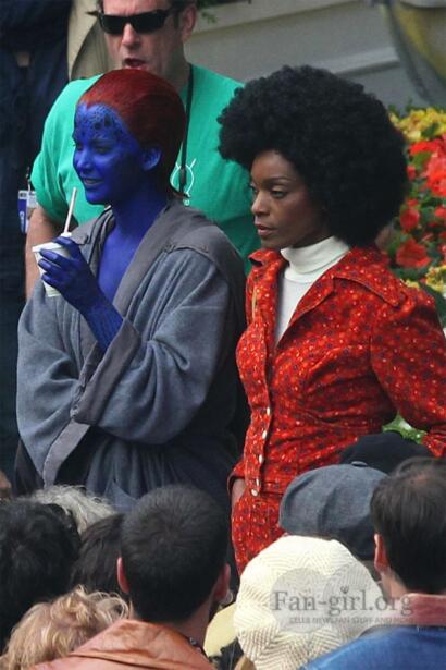 Celebrities on set: one with vibrant blue face paint, and the other with a large afro hairstyle.