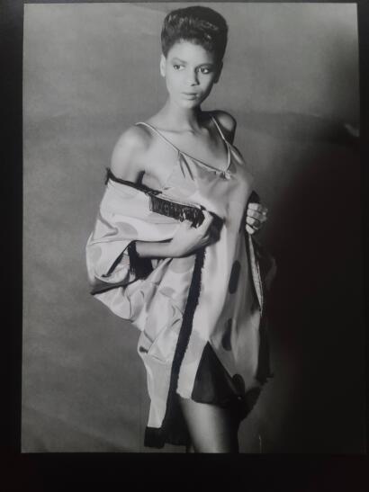 Black-and-white portrait of a woman in elegant, silky nightwear with fringe details, striking a confident pose.