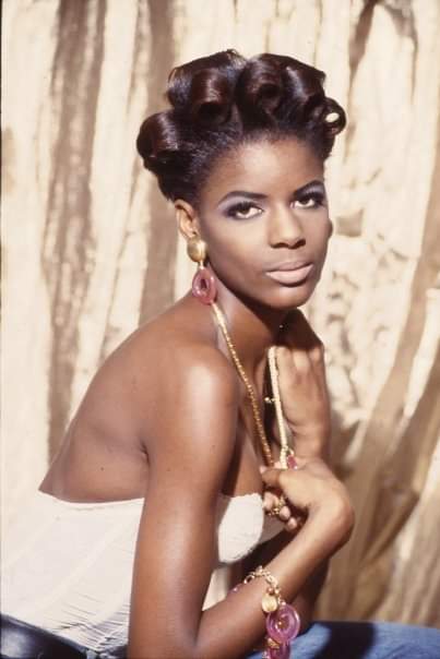 Elegant woman with elaborate vintage hairstyle and bold jewelry.