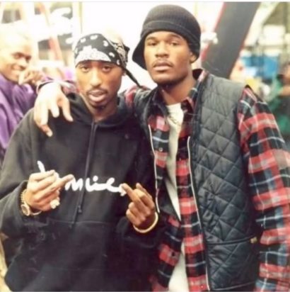 Two young men in casual streetwear pose at an indoor event, with a vibrant, lively background.