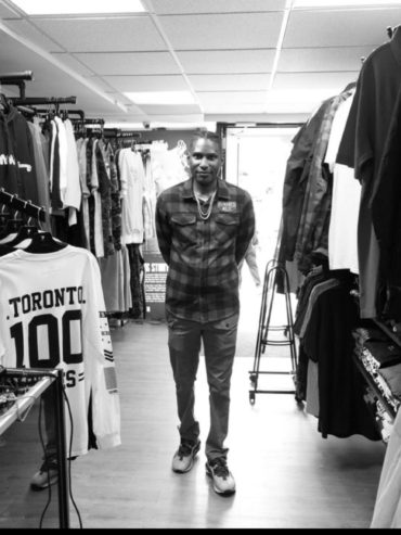 Person browsing through racks of casual clothing in a store.