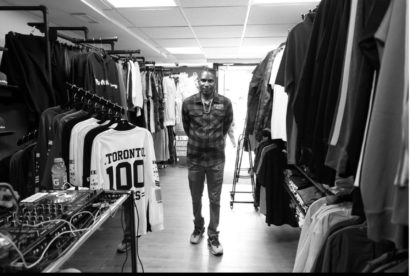 Person browsing through racks of casual clothing in a store.