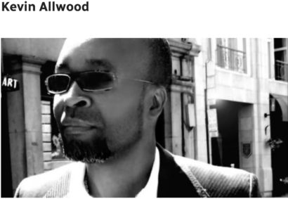 Kevin Allwood in stylish sunglasses, urban street scene backdrop.