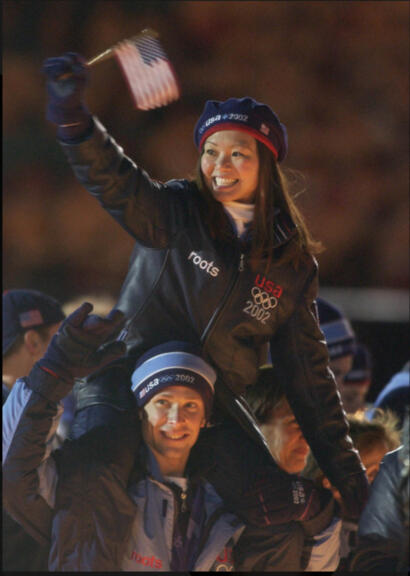 Celebrating the 2002 US Winter Olympics, athletes wear team gear at night.