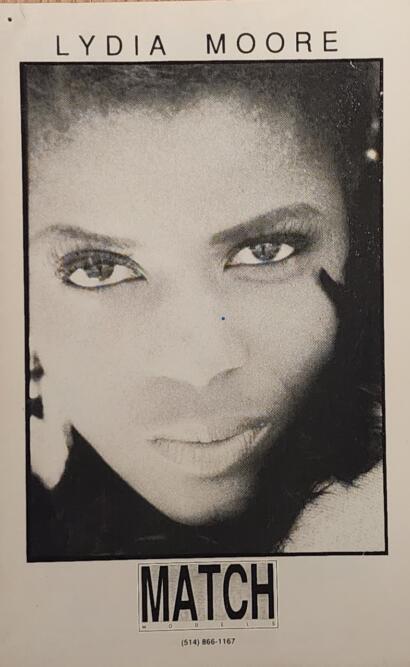 Black-and-white portrait of Lydia Moore, featuring bold makeup and a confident gaze.