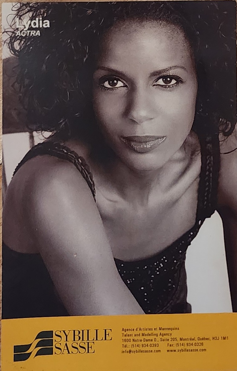 Black-and-white portrait of a woman with curly hair, wearing a sleeveless top, with a professional headshot style.