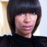 Close-up of a woman with a sleek, dark bob haircut, wearing a modern black top.