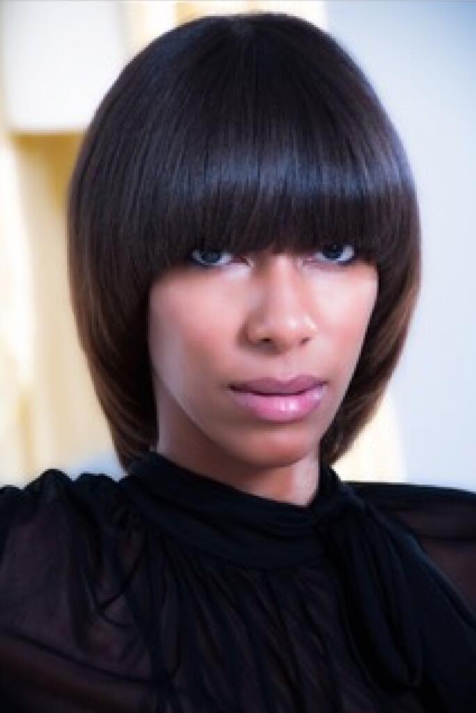 Close-up of a woman with a sleek, dark bob haircut, wearing a modern black top.