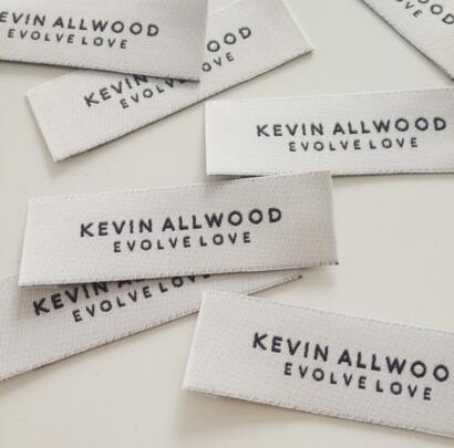 Clothing labels reading "Kevin Allwood Evolve Love" scattered on a white surface.