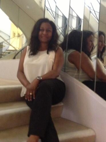 Woman sitting on stairs near mirrored wall in an elegant interior.
