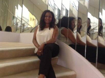 Woman sitting on stairs near mirrored wall in an elegant interior.