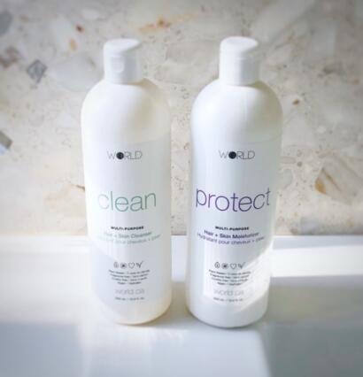 White bottles labeled "clean" and "protect" skin and hair products on a marble surface.