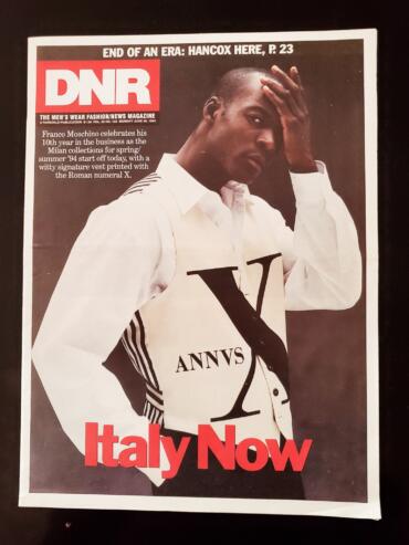 Fashion magazine cover featuring a model in a white shirt with black accents, holding his head.