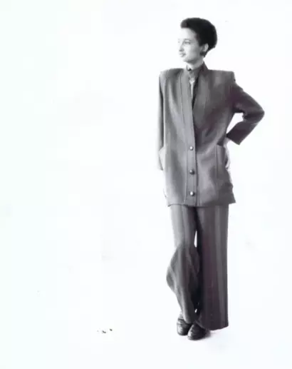 A woman in a tailored suit strikes a confident pose against a plain white background.