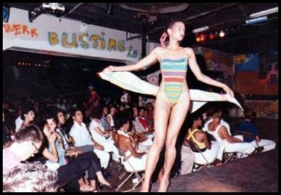 Model in a colorful striped swimsuit walks the runway at a fashion event.