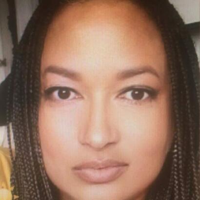 Close-up of a woman's face with braided hair, natural makeup, and neutral expression.