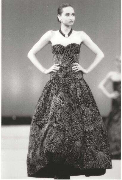 Elegant black evening gown with intricate feather-like patterns, accessorized with a statement necklace.