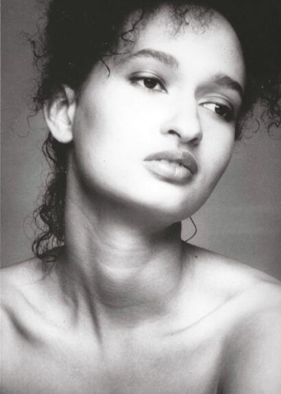 Black and white portrait of a woman with curly hair and confident expression.