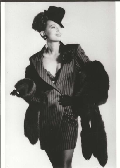 Vintage black and white portrait of a woman in a striped blazer, fur coat, and elegant hat.